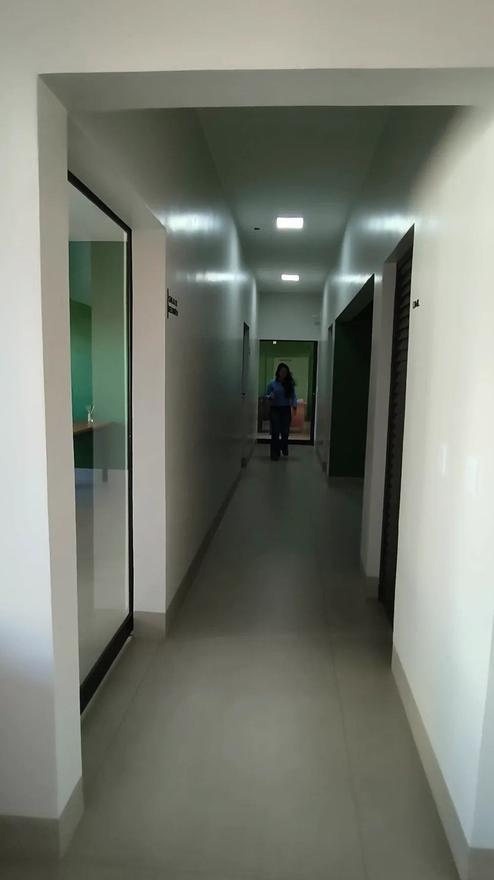 Corredor interno do bloco administrativo, com sala de reunião envidraçada